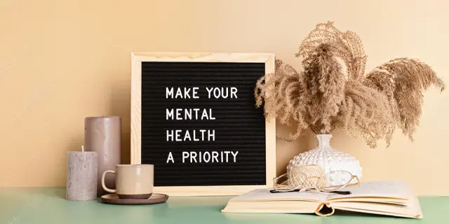A vase, plant, and chalkboard sign that says, "MAKE YOUR MENTAL HEALTH A PRIORITY"